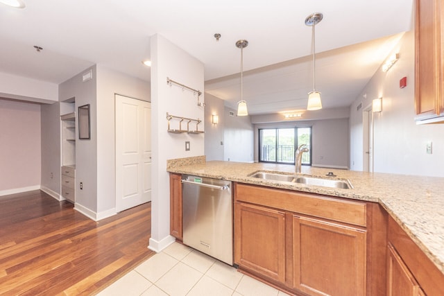 111 N Ashley St Unit 412, Ann Arbor, MI 48104 - kitchen featuring stainless steel dishwasher, brown cabinets, light stone counters, hanging light fixtures, and light wood-style floors