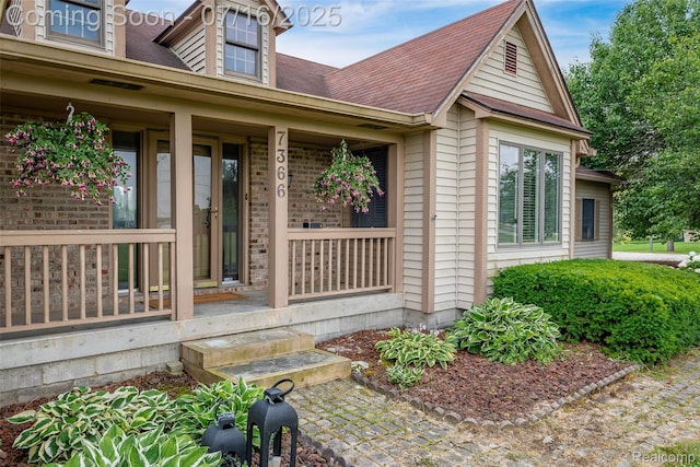 7366 E Maple Ave, Grand Blanc, MI 48439 - view of exterior entry with roof with shingles and a porch