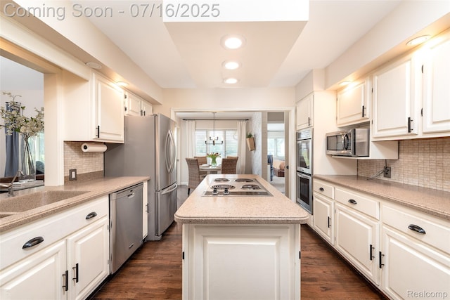 7366 E Maple Ave, Grand Blanc, MI 48439 - kitchen with a kitchen island, appliances with stainless steel finishes, white cabinetry, dark wood-style floors, and decorative backsplash