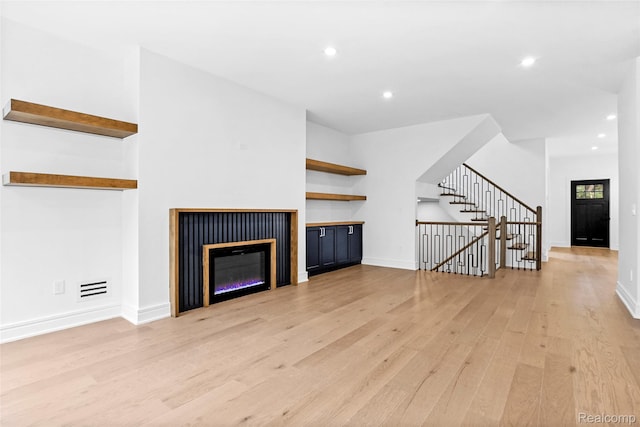 227 W Houstonia Ave, Royal Oak, MI 48073 - unfurnished living room with light wood-type flooring, recessed lighting, a glass covered fireplace, and stairway