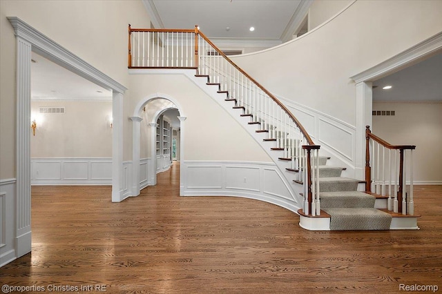 400 Hamilton Rd, Bloomfield, MI 48301 - staircase featuring a decorative wall, crown molding, a high ceiling, arched walkways, and wood finished floors