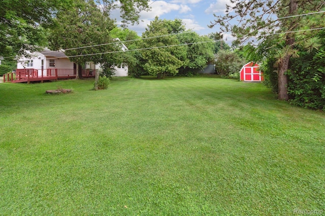 4415 Central St, Columbiaville, MI 48421 - view of grassy yard with a storage unit and a wooden deck