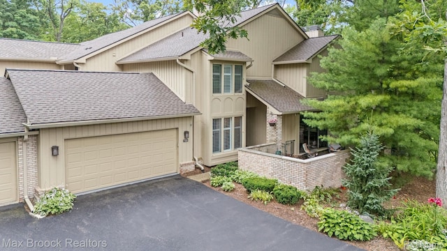 1109 Ivyglen Cir, Bloomfield Hills, MI 48304 - view of front facade featuring roof with shingles, driveway, brick siding, and an attached garage