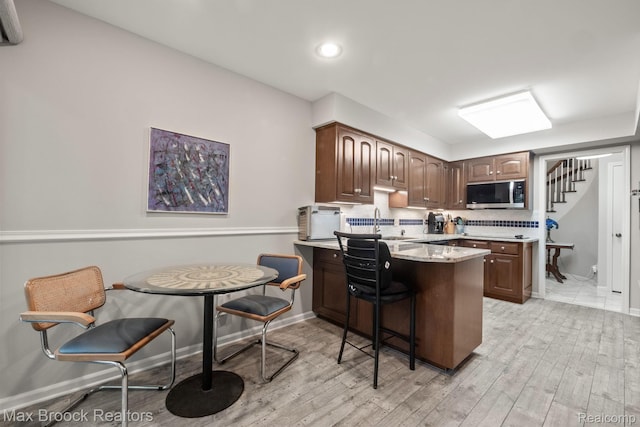 1109 Ivyglen Cir, Bloomfield Hills, MI 48304 - kitchen featuring stainless steel microwave, light wood-type flooring, a peninsula, a kitchen breakfast bar, and recessed lighting