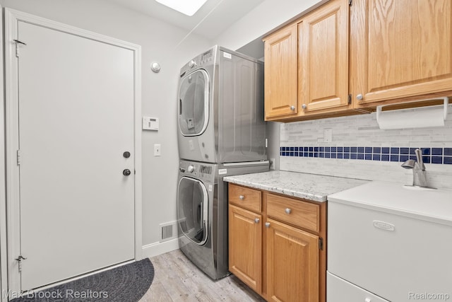 1109 Ivyglen Cir, Bloomfield Hills, MI 48304 - laundry area featuring stacked washer / drying machine, cabinet space, and light wood-style flooring