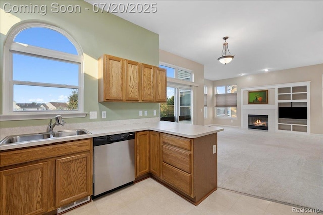 1145 York Ave, Howell, MI 48843 - kitchen with a peninsula, stainless steel dishwasher, light countertops, decorative light fixtures, and a glass covered fireplace