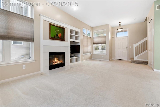 1145 York Ave, Howell, MI 48843 - unfurnished living room featuring built in shelves, carpet, a tile fireplace, and stairs