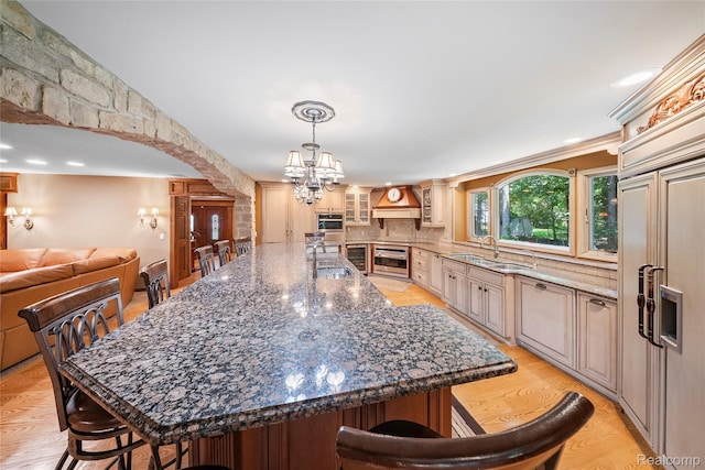 8931 Bridge Rd, Grosse Ile, MI 48138 - kitchen featuring a chandelier, a kitchen bar, premium range hood, glass insert cabinets, and a spacious island
