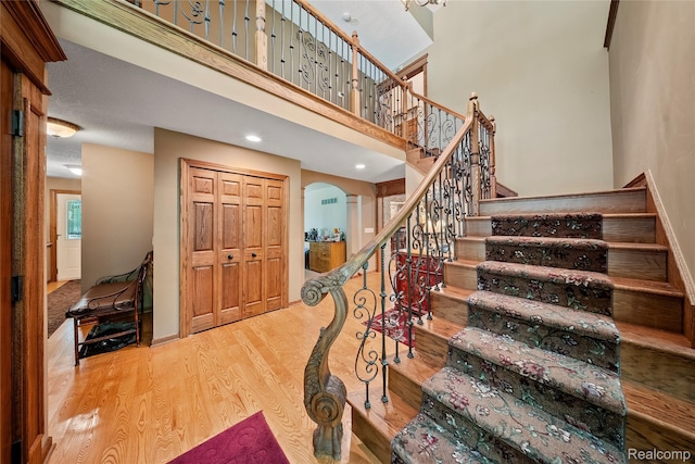 8931 Bridge Rd, Grosse Ile, MI 48138 - staircase with wood finished floors, arched walkways, recessed lighting, and a towering ceiling