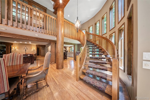 8931 Bridge Rd, Grosse Ile, MI 48138 - stairway with a towering ceiling, decorative columns, wood finished floors, recessed lighting, and a chandelier