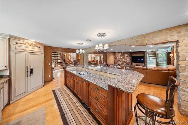 8931 Bridge Rd, Grosse Ile, MI 48138 - kitchen featuring a chandelier, light wood-style floors, pendant lighting, paneled fridge, and light stone countertops