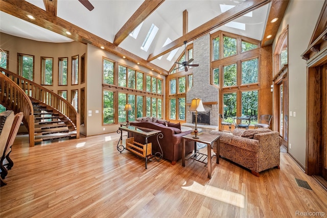 8931 Bridge Rd, Grosse Ile, MI 48138 - living room featuring ceiling fan, high vaulted ceiling, beamed ceiling, a skylight, and light wood-type flooring