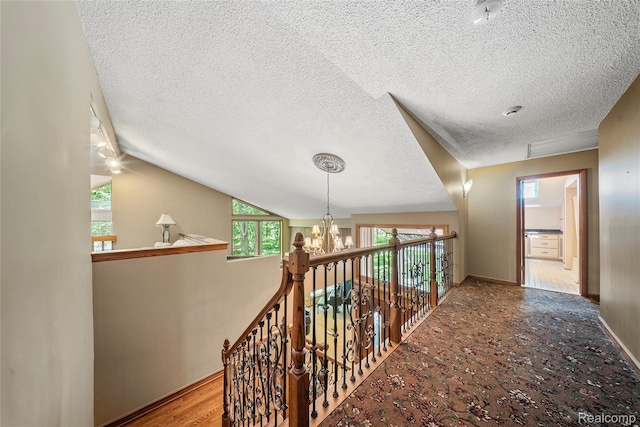8931 Bridge Rd, Grosse Ile, MI 48138 - hallway featuring a textured ceiling, a chandelier, vaulted ceiling, and an upstairs landing