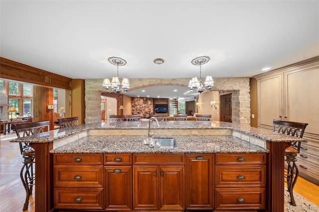 8931 Bridge Rd, Grosse Ile, MI 48138 - kitchen with a chandelier, a kitchen bar, pendant lighting, and decorative columns