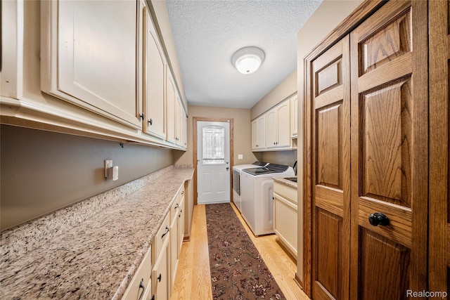8931 Bridge Rd, Grosse Ile, MI 48138 - laundry area with cabinet space, washing machine and clothes dryer, light wood-type flooring, and a textured ceiling