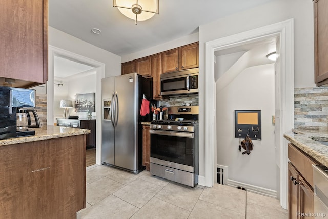 1405 Fielding St, Ferndale, MI 48220 - kitchen featuring stainless steel appliances, backsplash, light stone counters, and light tile patterned floors