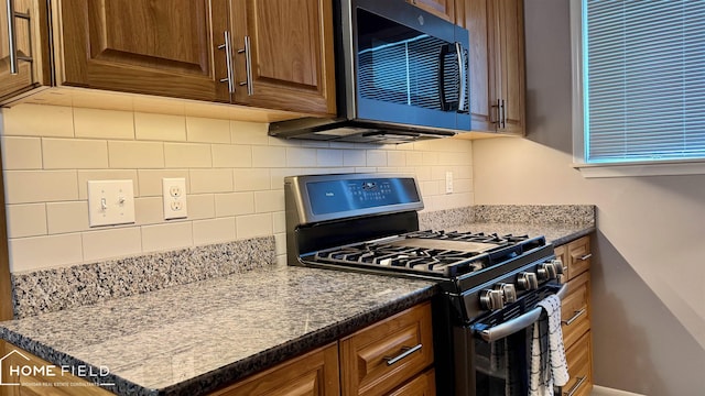 510 Martin St, Owosso, MI 48867 - kitchen with stainless steel appliances, decorative backsplash, and brown cabinets