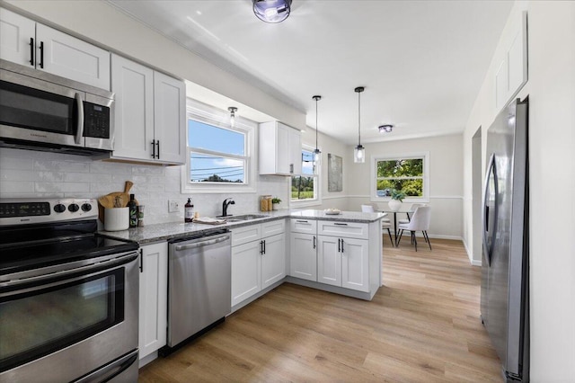 10965 Bunton Rd, Willis, MI 48191 - kitchen featuring appliances with stainless steel finishes, white cabinetry, tasteful backsplash, and light wood-style flooring