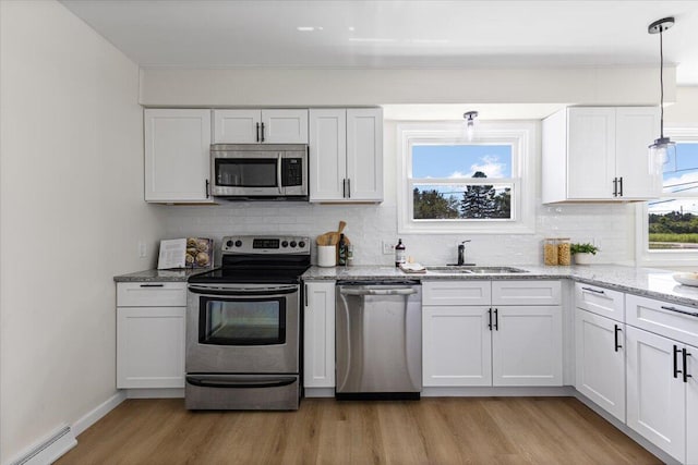 10965 Bunton Rd, Willis, MI 48191 - kitchen featuring appliances with stainless steel finishes, light wood-style flooring, tasteful backsplash, and white cabinets
