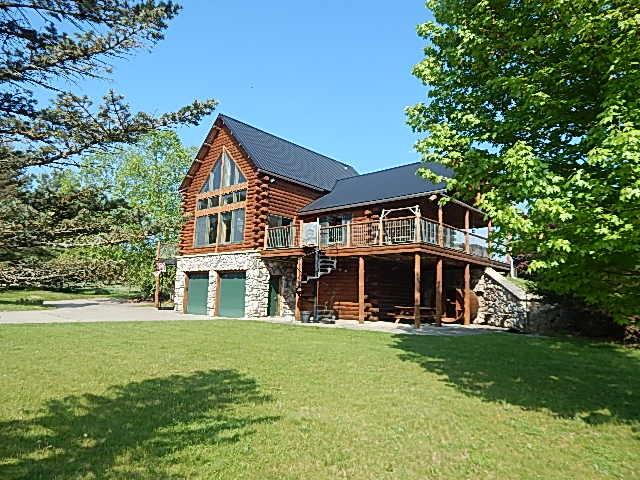 8475 Gurd Rd, Dowling, MI 49050 - view of front facade featuring log exterior, a garage, a wooden deck, and a front lawn