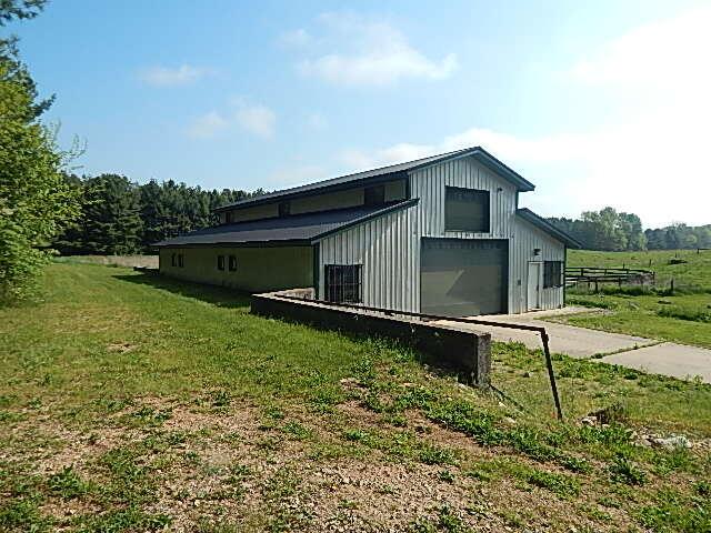 8475 Gurd Rd, Dowling, MI 49050 - view of property exterior featuring a lawn, board and batten siding, a garage, driveway, and an outdoor structure