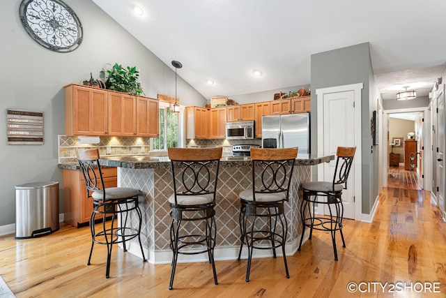 3981 Acadia Dr, Hudsonville, MI 49426 - kitchen with stainless steel appliances, decorative backsplash, a breakfast bar, light wood-style flooring, and high vaulted ceiling