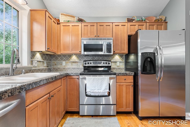 3981 Acadia Dr, Hudsonville, MI 49426 - kitchen with appliances with stainless steel finishes, light wood finished floors, dark countertops, and tasteful backsplash