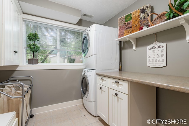 3981 Acadia Dr, Hudsonville, MI 49426 - laundry area with stacked washer / drying machine, cabinet space, light tile patterned flooring, and a textured ceiling
