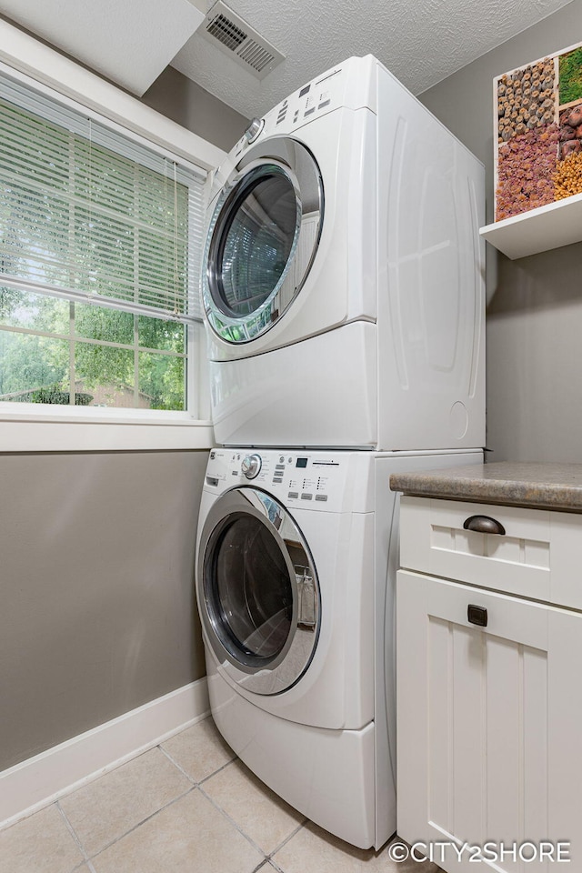 3981 Acadia Dr, Hudsonville, MI 49426 - laundry area with estacked washer and dryer, light tile patterned floors, and cabinet space