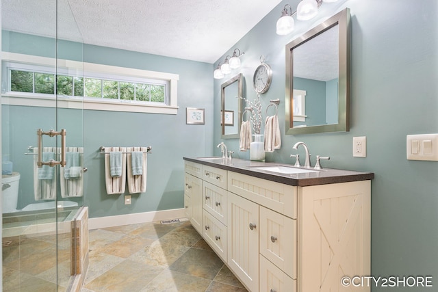 3981 Acadia Dr, Hudsonville, MI 49426 - bathroom with stone tile floors, double vanity, a textured ceiling, and an enclosed shower