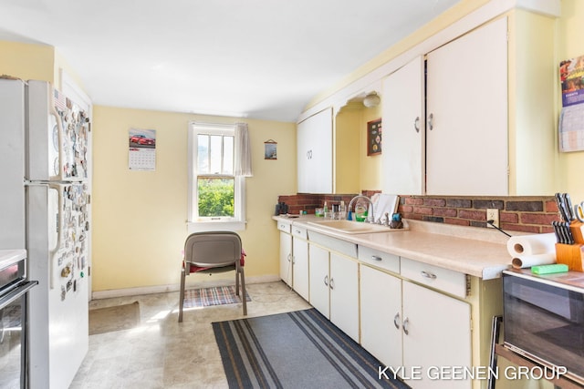 747 State St, Holland, MI 49423 - kitchen with freestanding refrigerator, light countertops, backsplash, oven, and white cabinetry