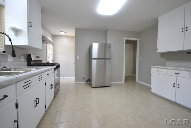304 N Van Buren St, Tecumseh, MI 49286 - kitchen featuring freestanding refrigerator, stainless steel range with gas stovetop, light countertops, under cabinet range hood, and white cabinetry