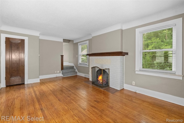 619 Frank St, Flint, MI 48504 - unfurnished living room featuring a fireplace, wood finished floors, and stairs