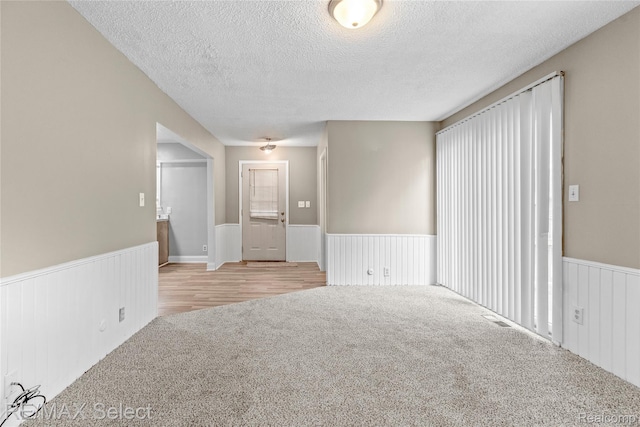 619 Frank St, Flint, MI 48504 - empty room featuring wainscoting, a textured ceiling, and carpet flooring