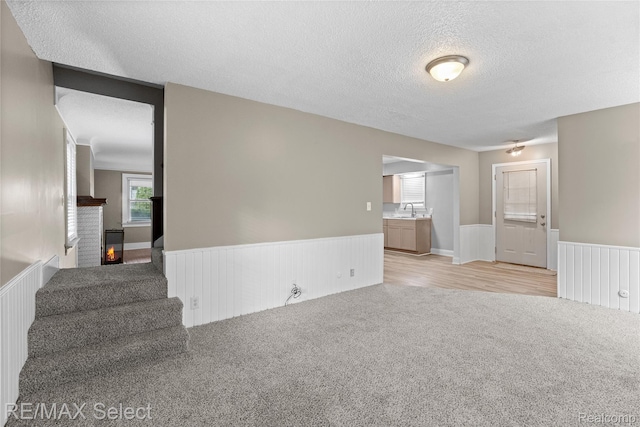619 Frank St, Flint, MI 48504 - unfurnished living room featuring wainscoting, light colored carpet, a textured ceiling, and stairs
