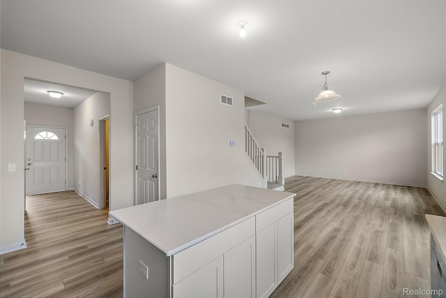 21008 Campolina Dr, South Lyon, MI 48178 - kitchen featuring light wood-type flooring, white cabinets, light countertops, a kitchen island, and hanging light fixtures