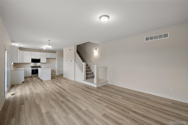 21008 Campolina Dr, South Lyon, MI 48178 - unfurnished living room with light wood finished floors and stairs