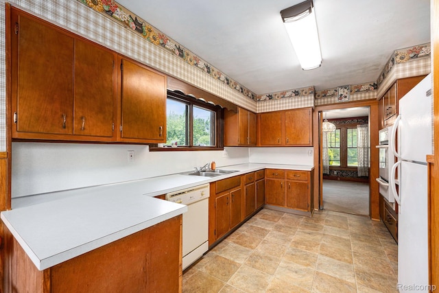 1615 W Genesee St, Lapeer, MI 48446 - kitchen featuring white appliances, stone finish flooring, brown cabinetry, light countertops, and wallpapered walls