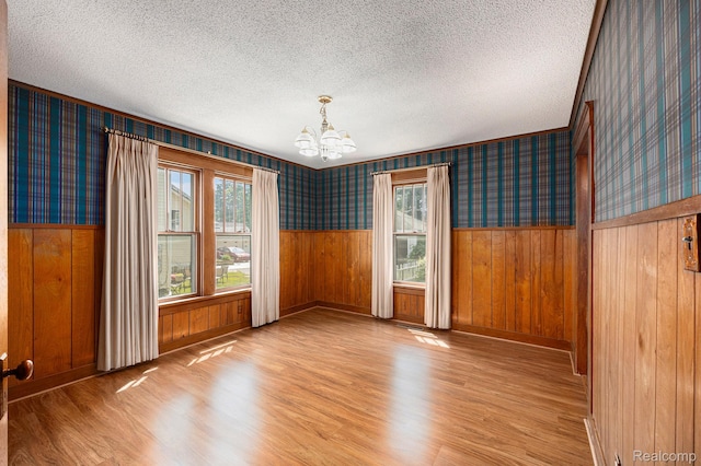 1615 W Genesee St, Lapeer, MI 48446 - spare room featuring wallpapered walls, light wood-style floors, a textured ceiling, a chandelier, and wainscoting