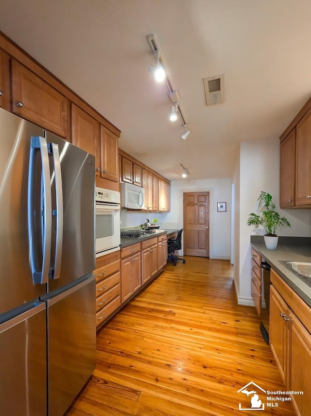 8 E Front St, Monroe, MI 48161 - kitchen featuring stainless steel appliances, dark countertops, brown cabinetry, and light wood-style floors
