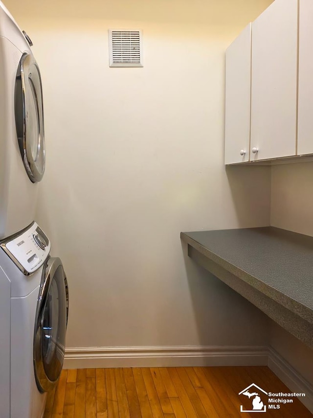 8 E Front St, Monroe, MI 48161 - laundry area with cabinet space, stacked washer / drying machine, and wood finished floors