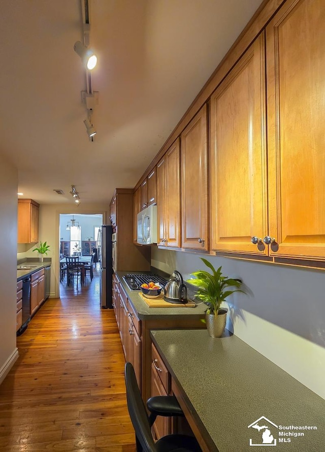 8 E Front St, Monroe, MI 48161 - kitchen featuring stainless steel appliances, brown cabinets, rail lighting, and wood-type flooring