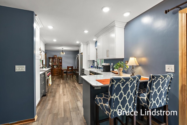 15520 157th Ave, Big Rapids, MI 49307 - kitchen with appliances with stainless steel finishes, white cabinetry, a breakfast bar area, recessed lighting, and wood finished floors