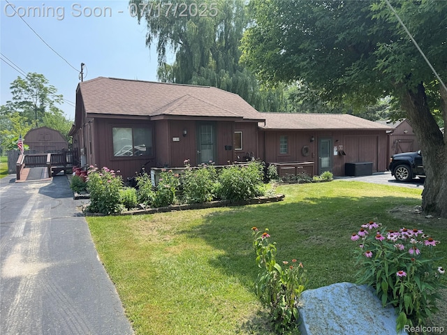 2185 Roslyn Ave, Flint, MI 48532 - view of front of home featuring a front lawn, roof with shingles, asphalt driveway, and board and batten siding