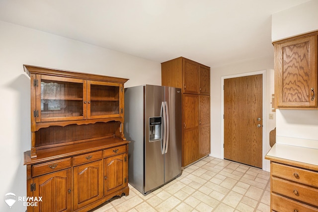 8208 E Potter Rd, Davison, MI 48423 - kitchen with stainless steel refrigerator with ice dispenser, brown cabinets, glass insert cabinets, and light countertops