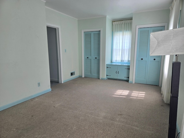 1115 W Maumee St, Adrian, MI 49221 - unfurnished bedroom with multiple closets, light colored carpet, and crown molding