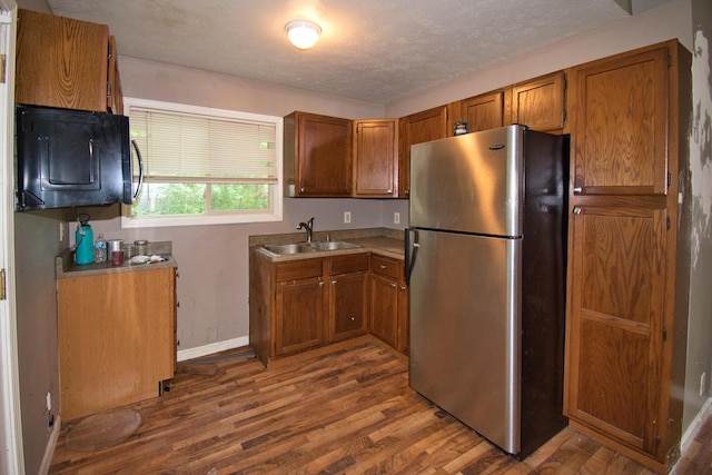 23627 Glenwood Rd, Cassopolis, MI 49031 - kitchen with freestanding refrigerator, brown cabinetry, dark wood-style flooring, a textured ceiling, and light countertops