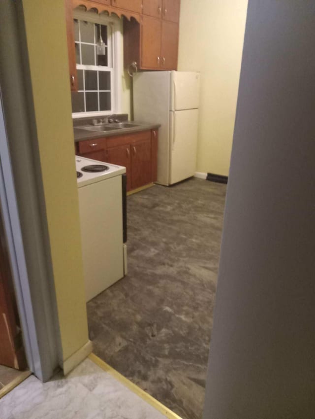 kitchen featuring white appliances, dark colored carpet, and brown cabinetry