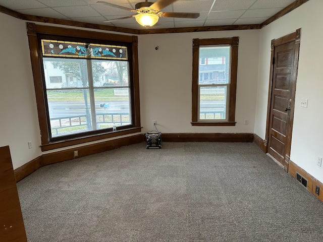 carpeted spare room with a paneled ceiling, ceiling fan, and plenty of natural light