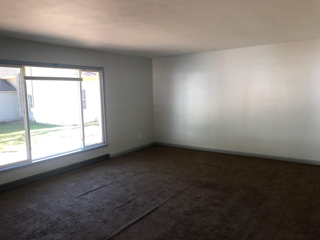 spare room featuring carpet floors and baseboards